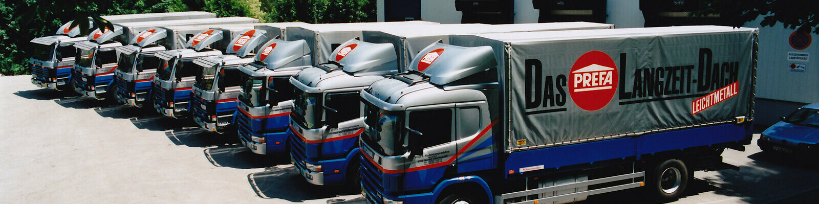 A row of eight former PREFA lorries in blue and silver with PREFA logo 