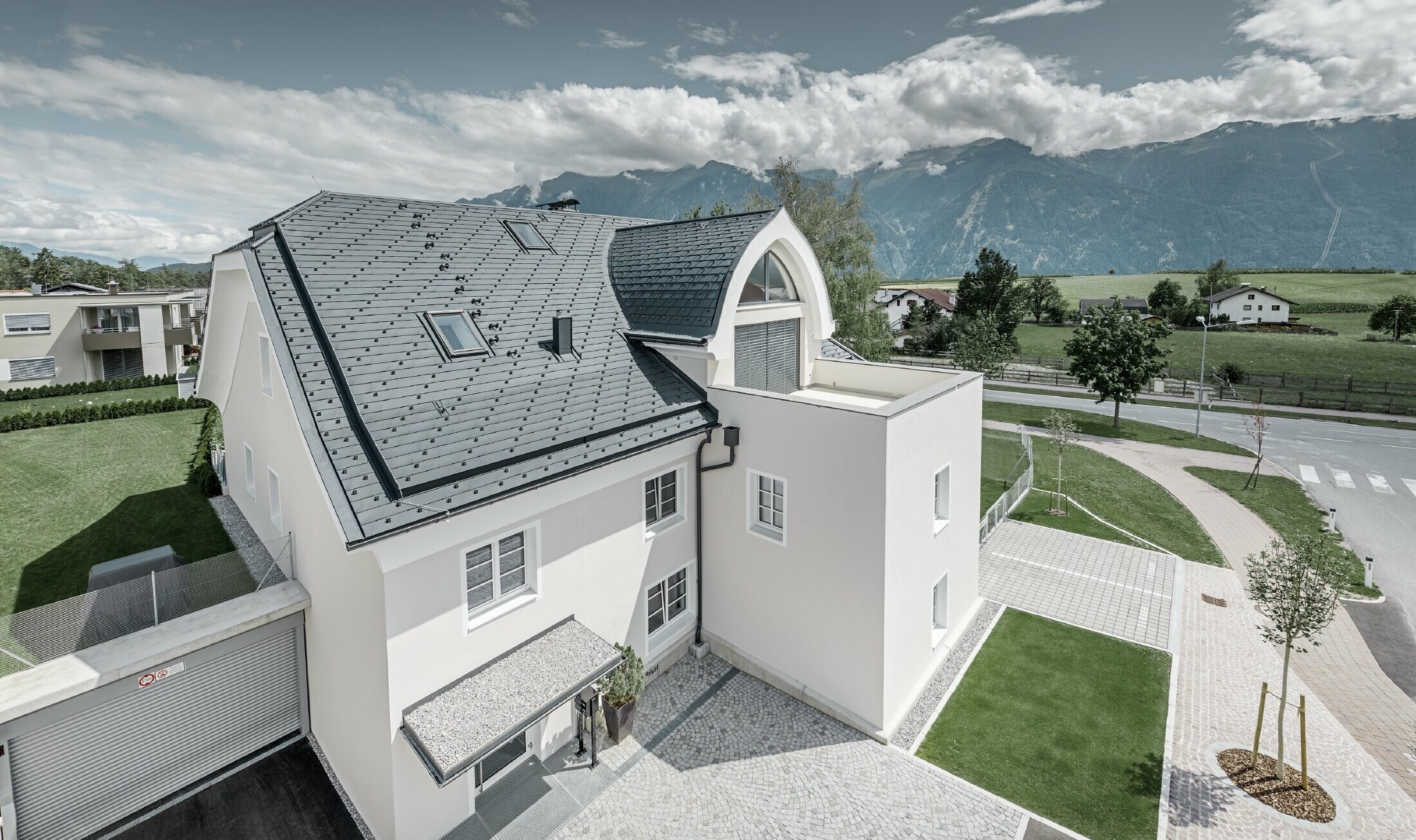 Newly refurbished residential building with new PREFA roof. The half hipped roof with pointed barrel dormer and loggia were covered with PREFA aluminium shingles in anthracite. PREFA snow guards, window surround and gutters were also installed.