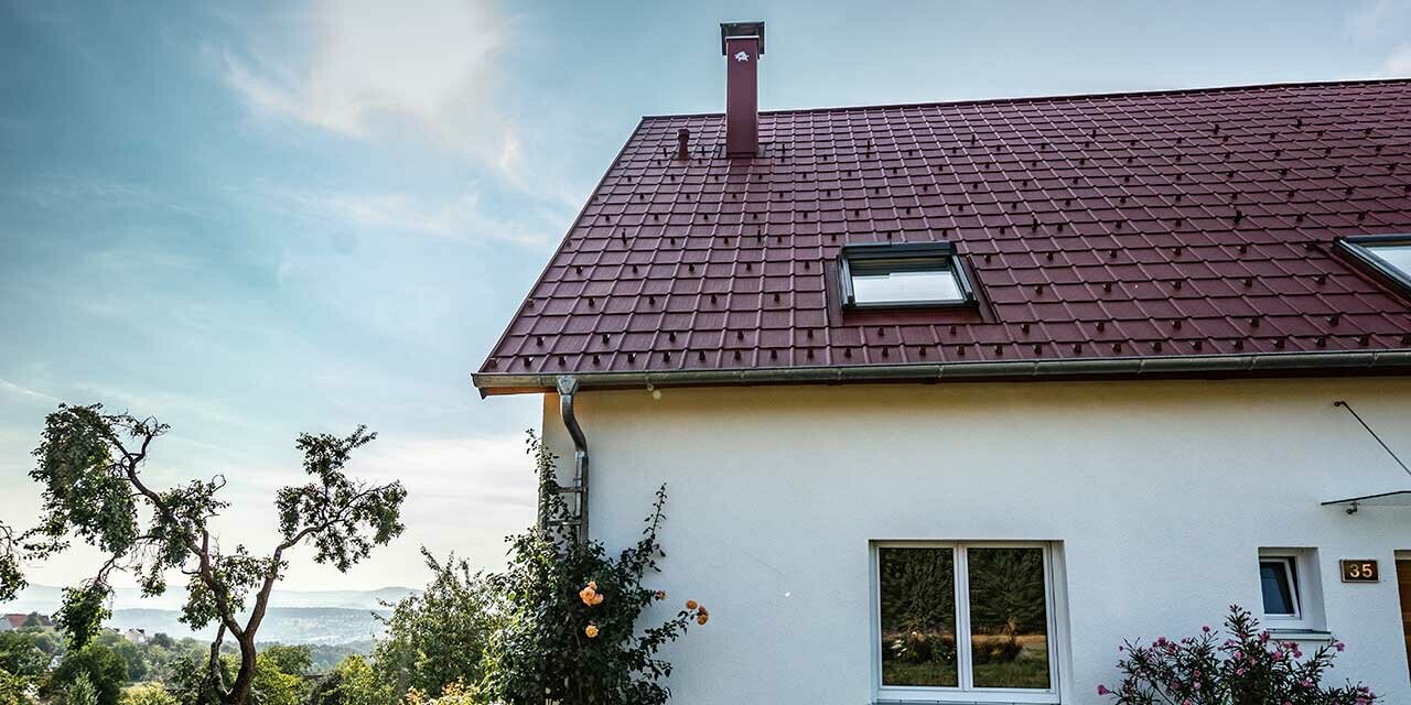 Rural cottage with refurbished roof using the PREFA roof tile in oxide red, roof window and chimney surround.