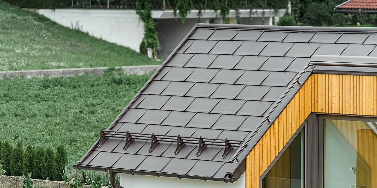 Gabled roof of a residential building covered with the PREFA R.16 roof tile in nut brown; the PREFA snow guard system was also used;