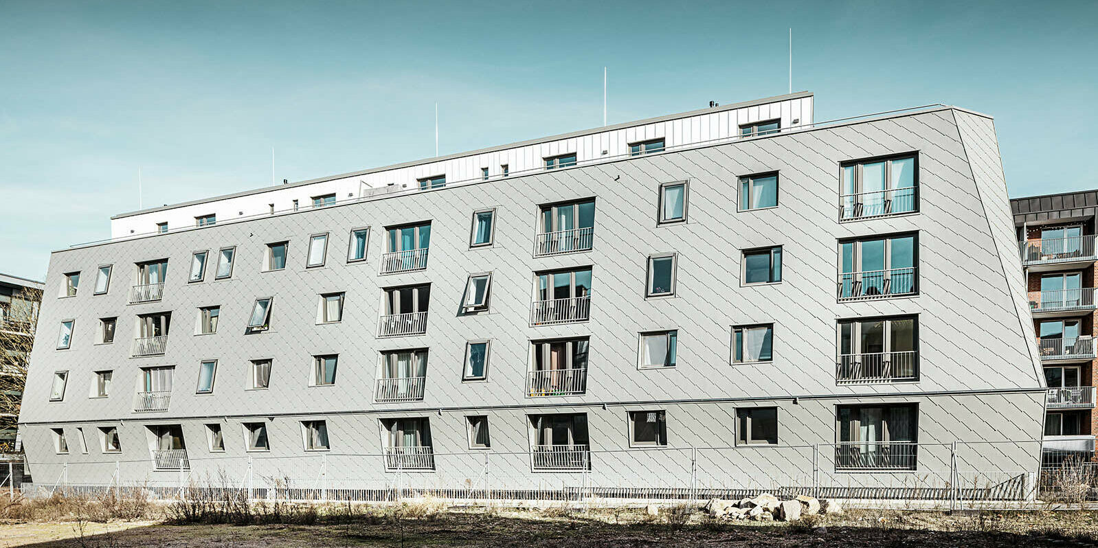 The picture shows the house in Harburg's inland harbour by day, which was roofed with PREFA rhomboid façade tiles 44x44 and Prefalz.