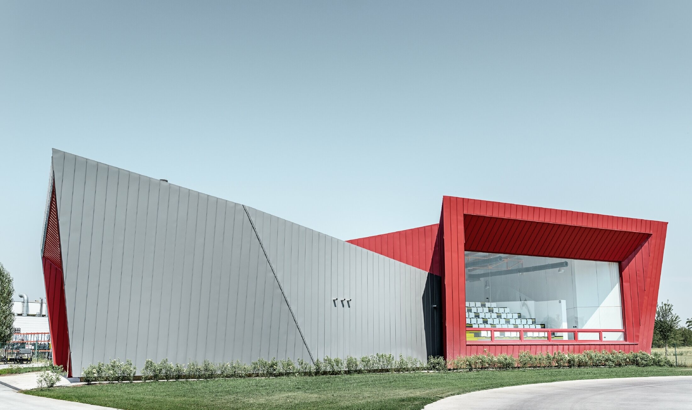 Dieci’s modern training centre in Montecchio Emilia (Italy), with a tribune displaying an aluminium façade in light grey Prefalz and crimson Falzonal
