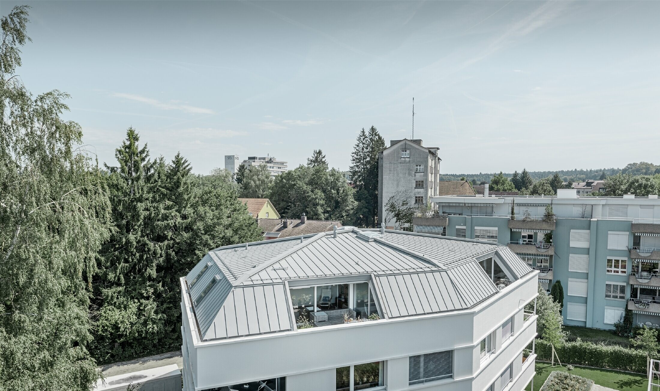 Roof of an apartment building covered with the PREFA Prefalz in patina grey with loggia.