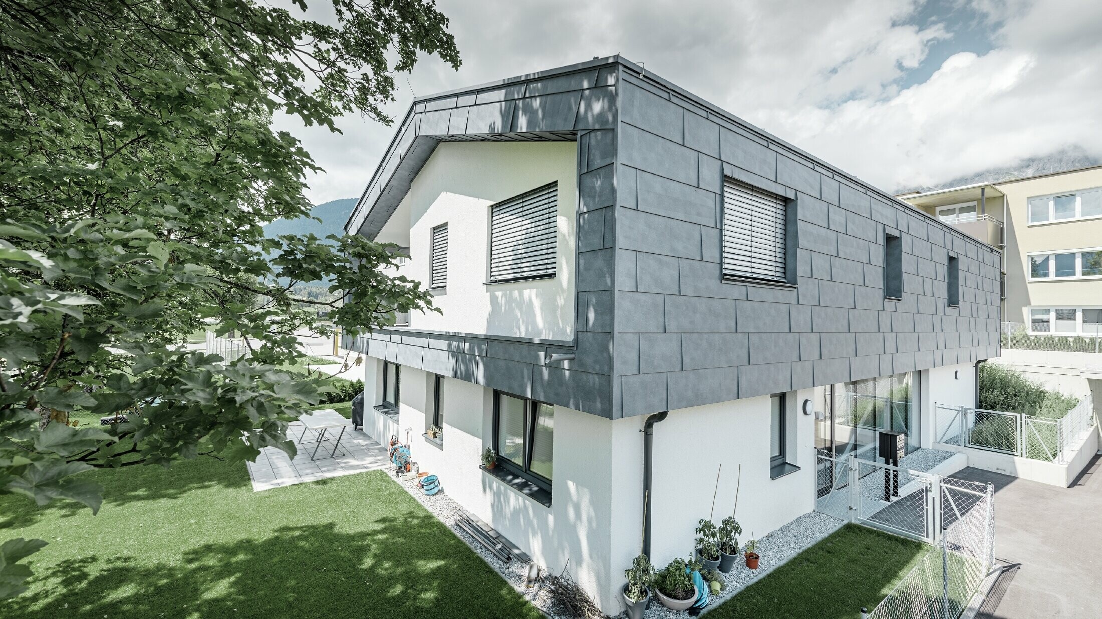 Addition of a modern storey on a residential building with flat gabled roof and no soffit; the PREFA FX.12 façade panel in stone grey was used for the façade cladding.