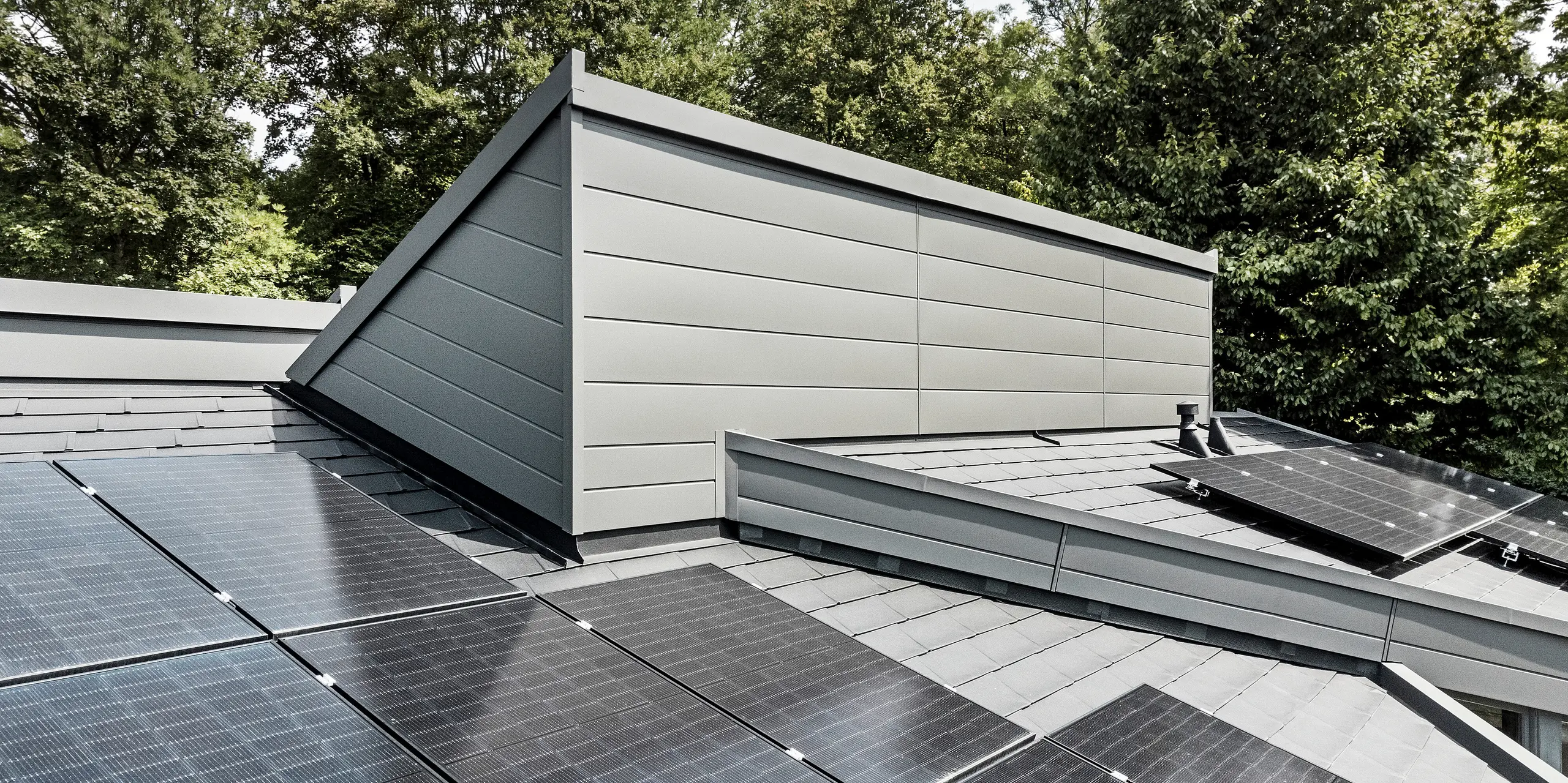 Ein Einfamilienhaus, das mit PREFA Dachschindeln DS.19 in schwarz eingedeckt wurde. Für Teile der Fassade wurden PREFA Sidings in P.10 dunkelgrau verwendet. 