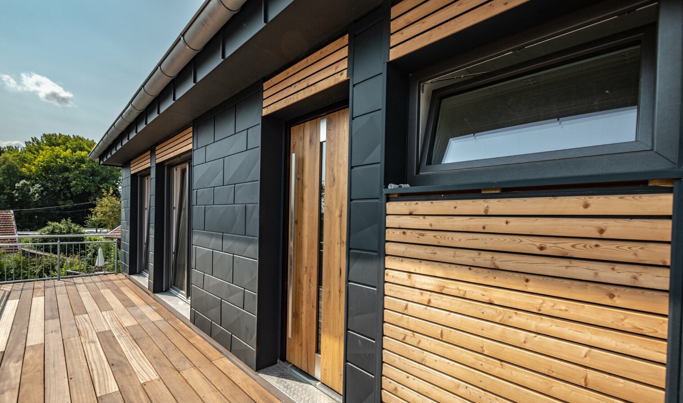 Façade design by mixing aluminium – PREFA Siding.X in anthracite – and horizontal wooden slats.