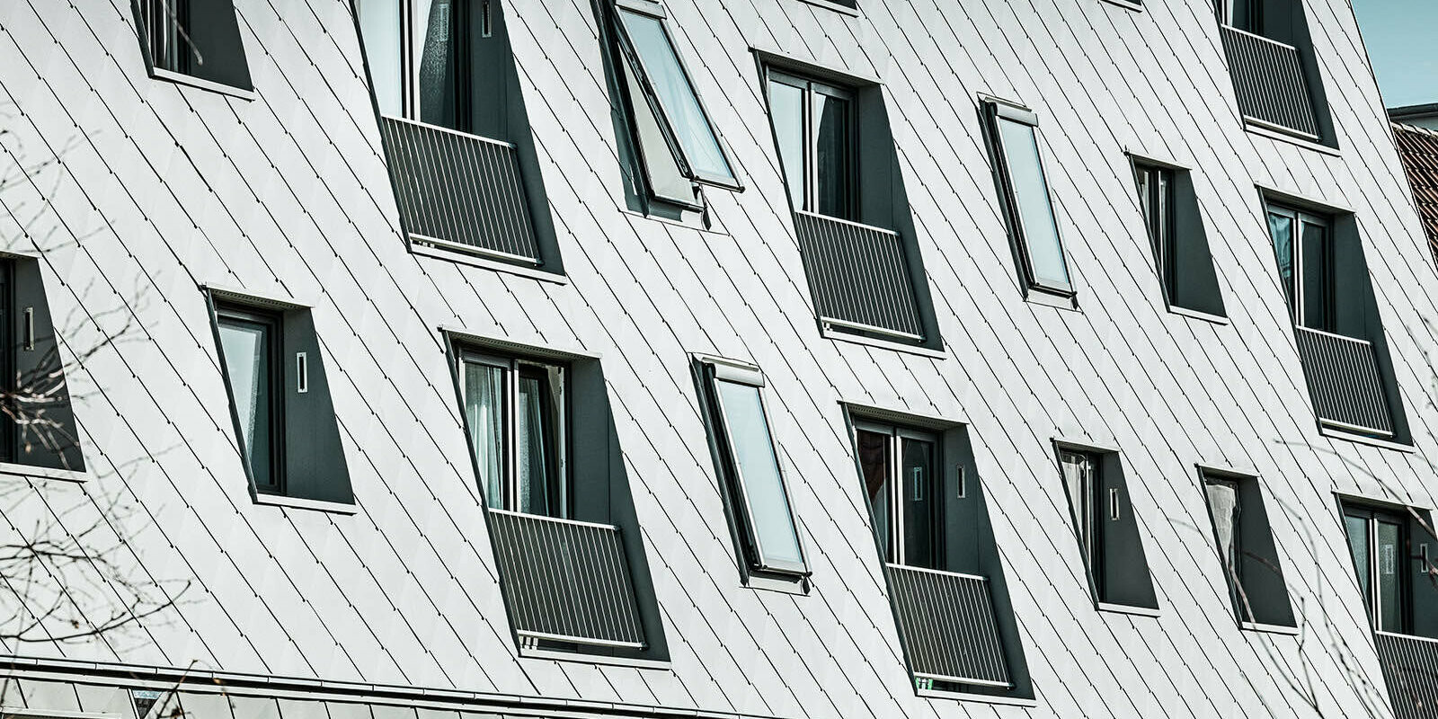 The picture shows the zinc-grey PREFA rhomboid façade tiles in P.10, which decorate the façade of the building.