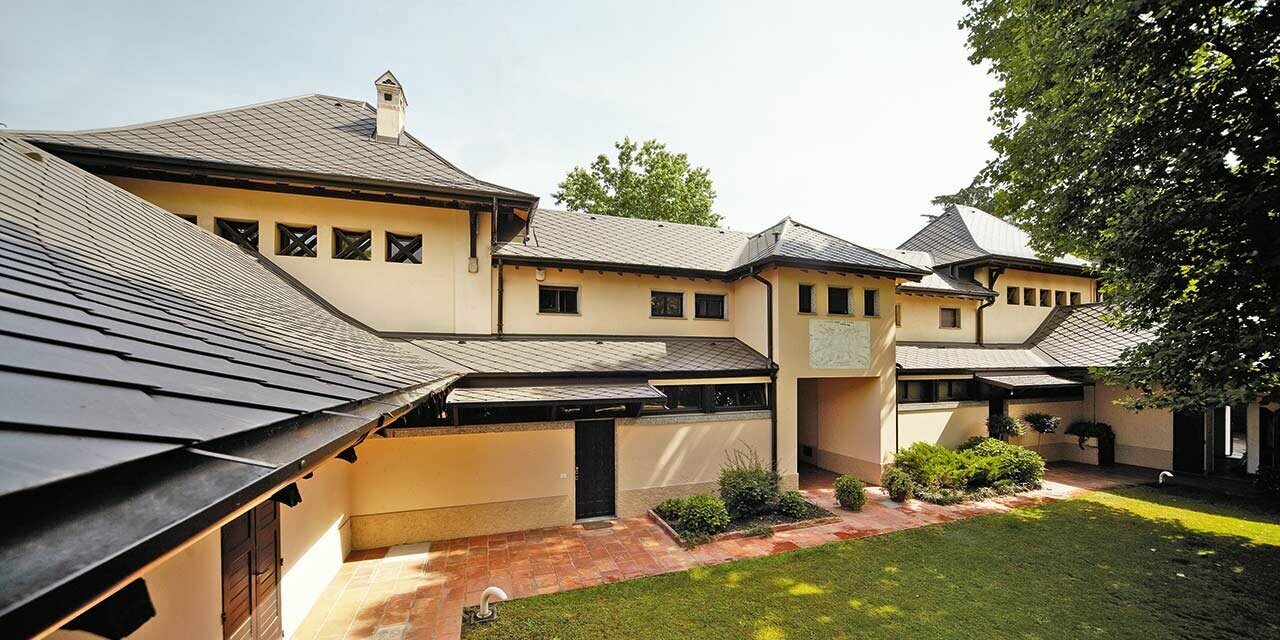 Italian villa with rhomboid roof in P.10 brown by PREFA with beige façade colour with shady inner courtyard