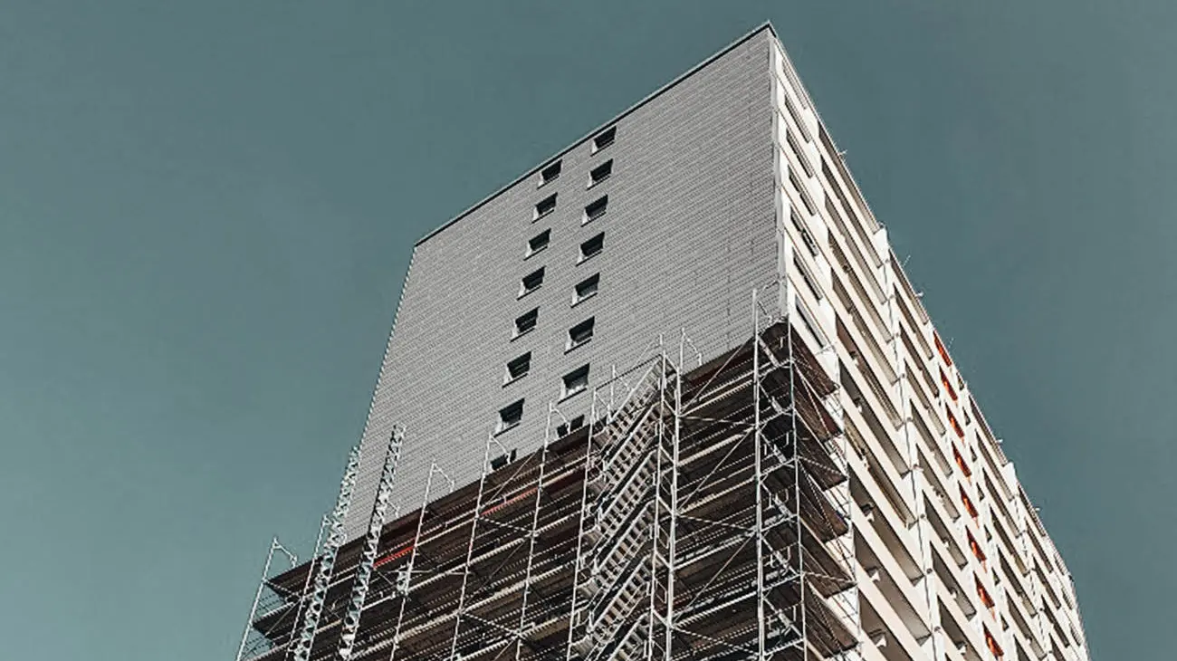 Lateral view of the high-rise during the façade renovation. The scaffold around the building can be seen.