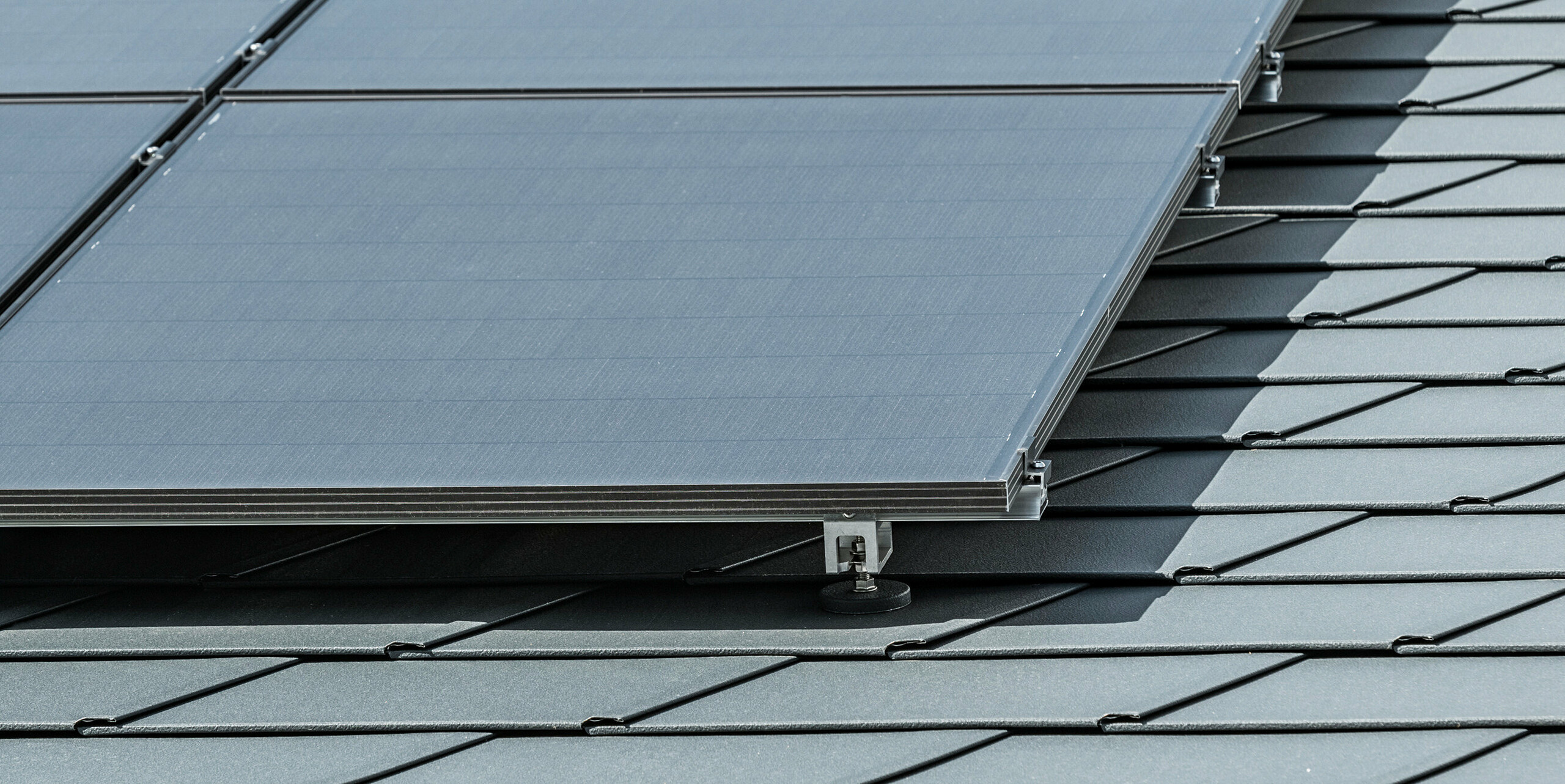 Close-up of a photovoltaic system mounted on PREFA roof shingles DS.19 in P.10 anthracite with PREFA Solar bracket Vario