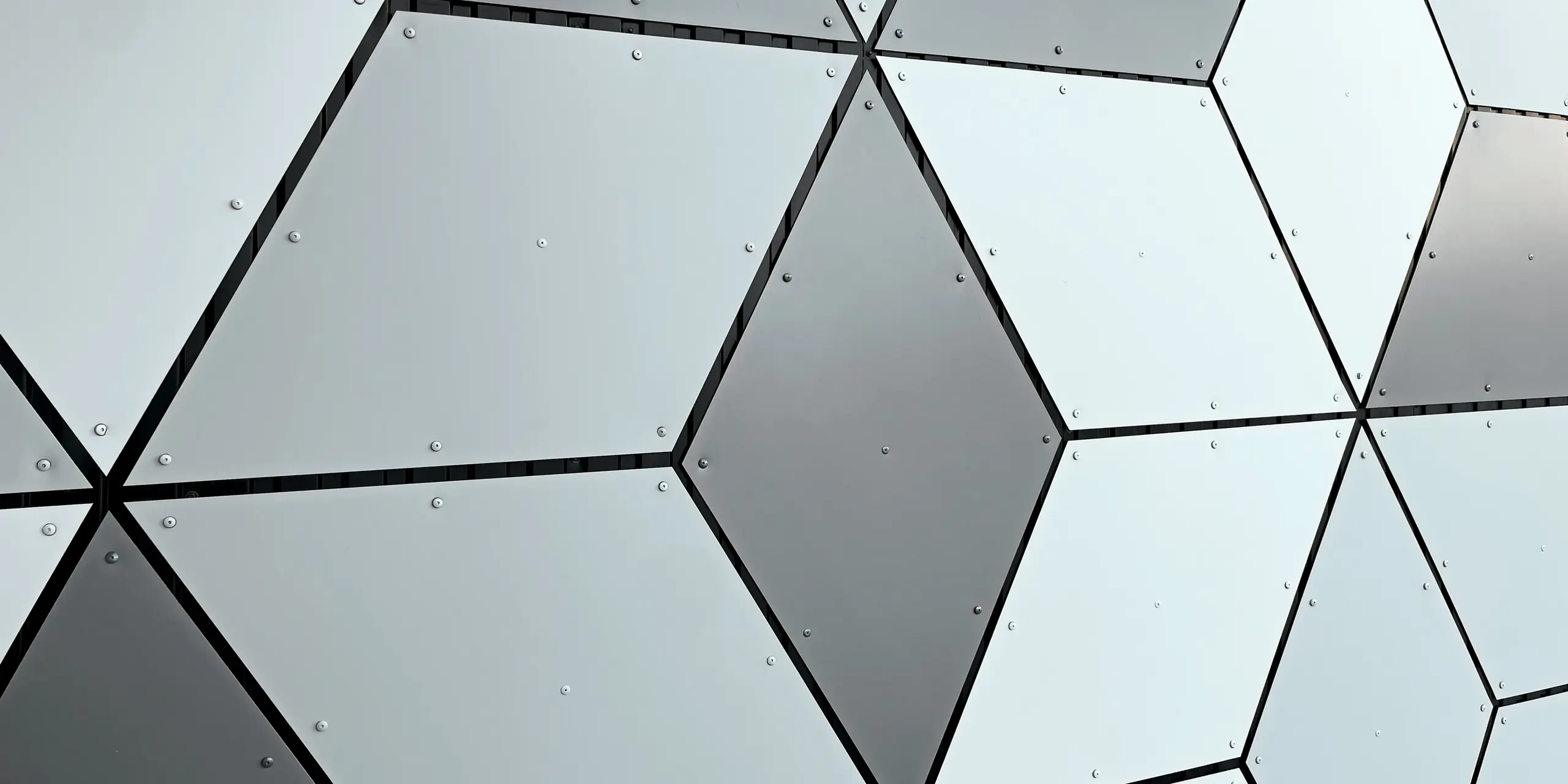 Detailaufnahme der Fassade der Seilbahnstation in Les Deux Alpes. Die PREFABOND Aluminium Verbundplatten sind in Rautenform angeordnet. Die faszinierende Kombination aus Weiß- und Grautönen erzeugt ein modernes, geometrisches Muster. Die solide Befestigung mit Schrauben unterstreicht die langlebige und widerstandsfähige Bauweise, die auch extremen Wetterbedingungen im Hochgebirge standhält.