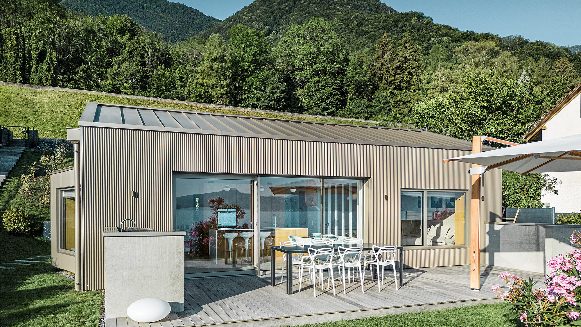 Side view of the lake house with a view of the terrace and a mountainous landscape in the background.