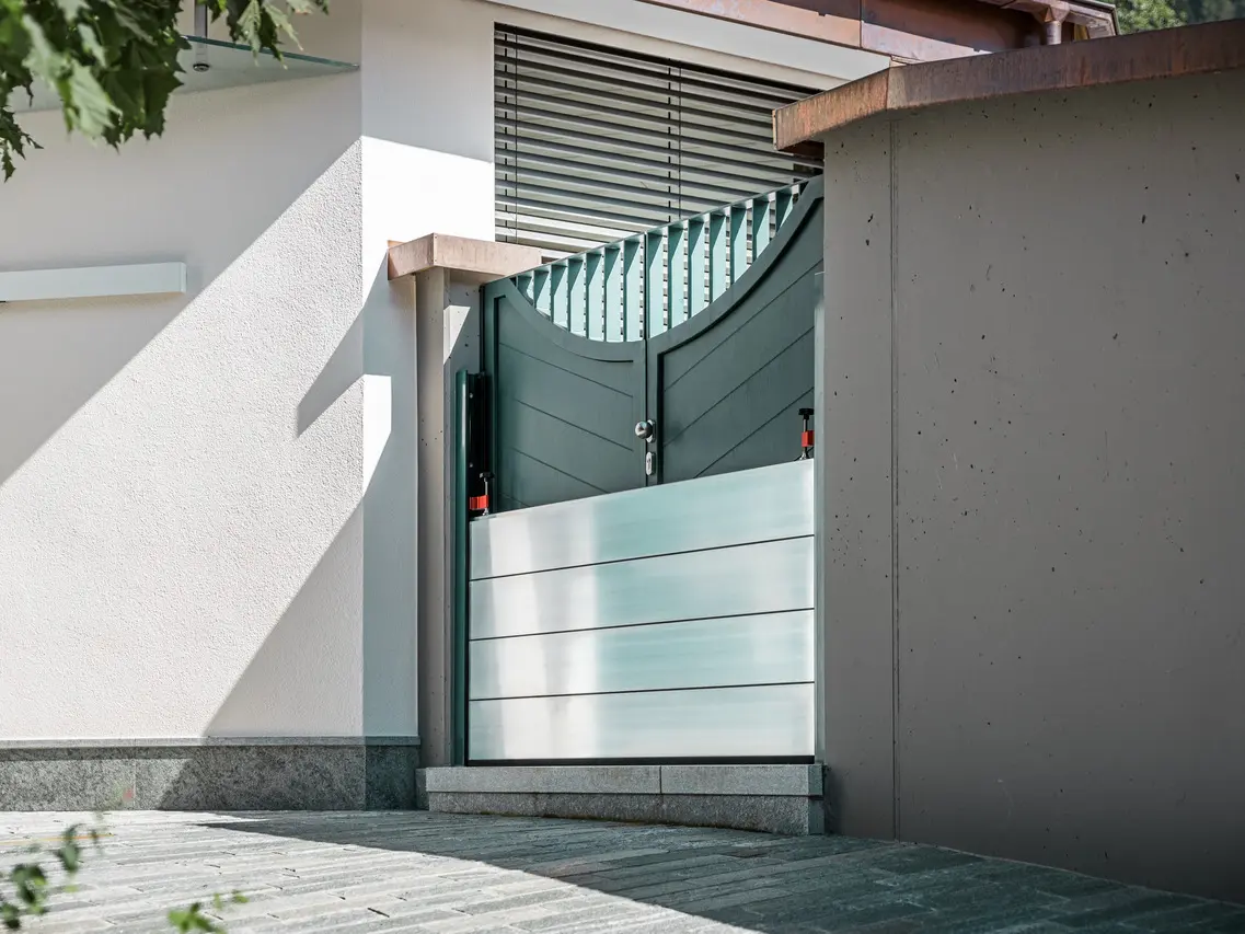 The picture shows a green entrance gate. PREFA's mobile flood protection was installed in front of it to prevent water from entering.