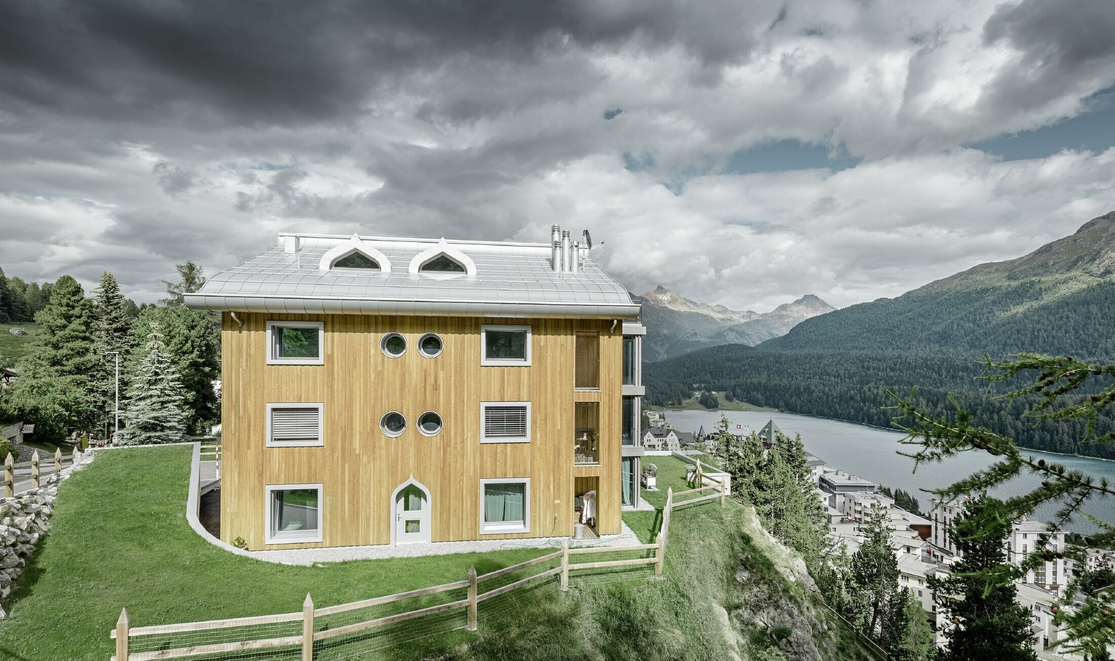 Residential complex in St. Moritz (Switzerland) with a wooden façade and an aluminium roof with undulating eaves in metallic silver