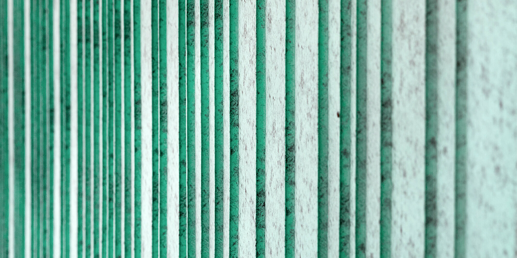 Detailed view of the patina green aluminium façade, rhythmized with differently wide trays. The colour creates a speckled appearance.