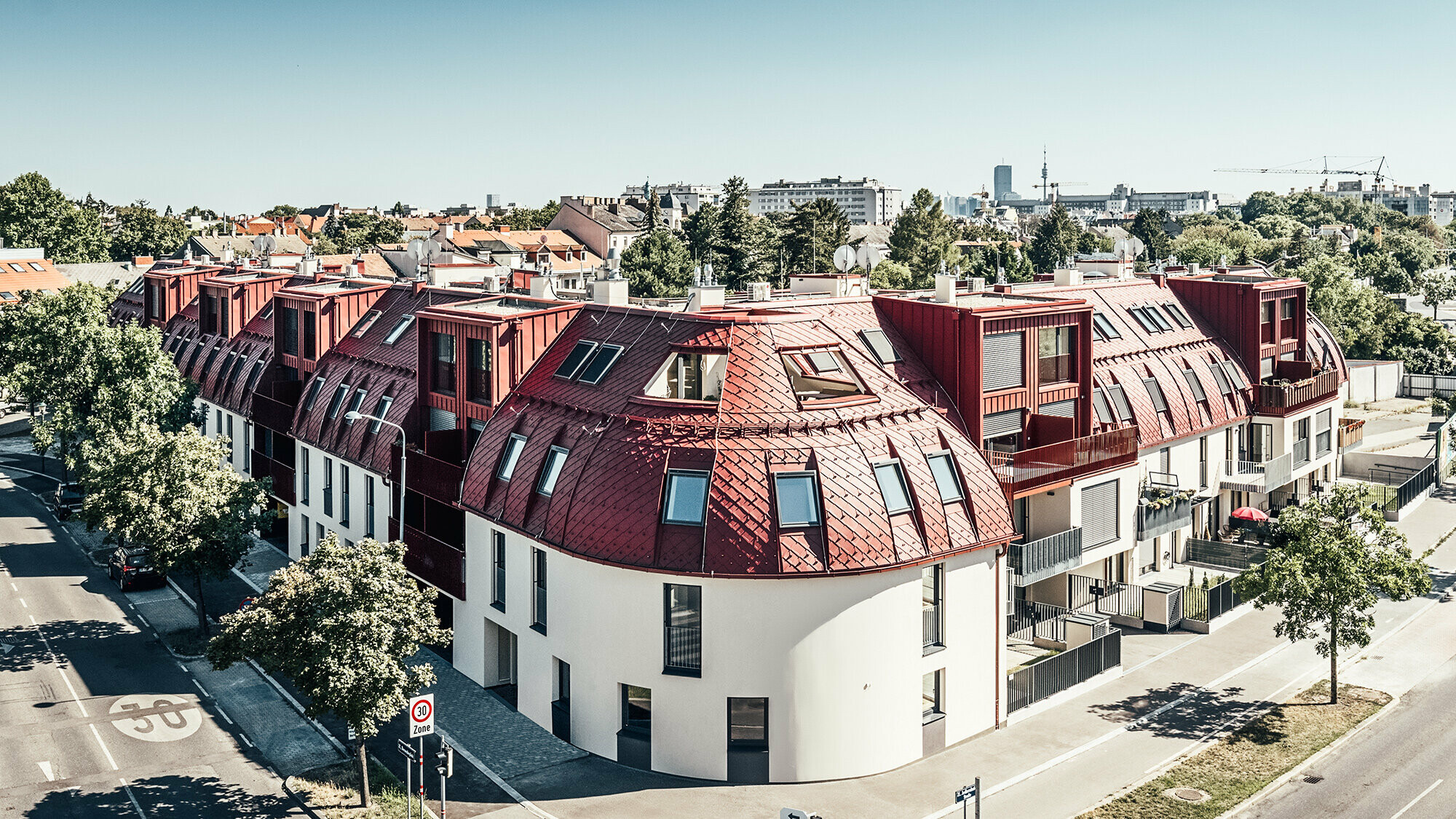 Street view of the residential complex Schöneck 13 with a rounded roofscape, designed by the architectural office schneider+schumacher.