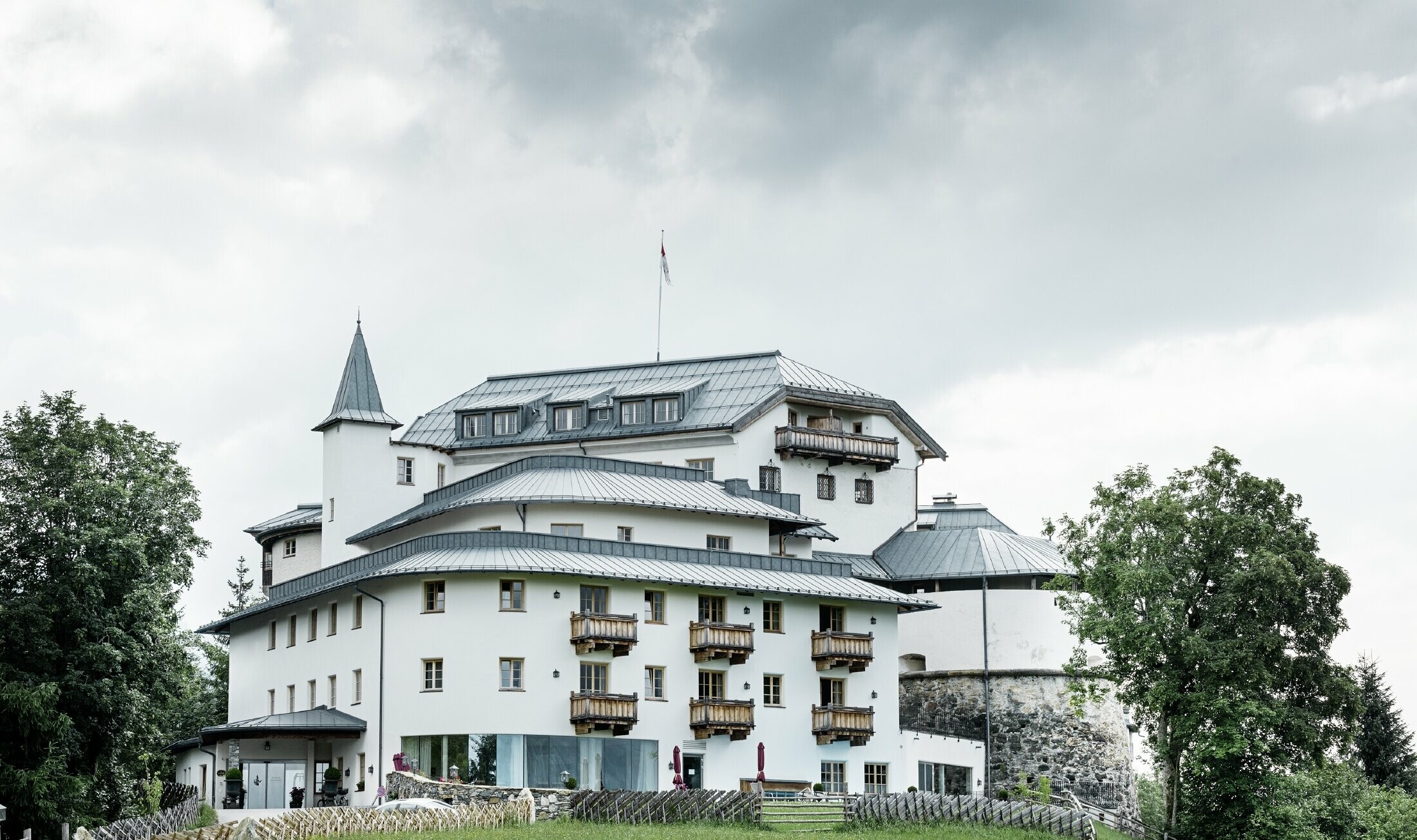 Mittersill Castle surrounded by trees and mountains with a renovated Prefalz roof in stone grey