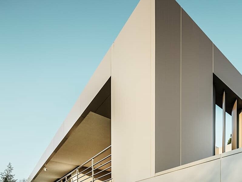 Back view, wooden terrace below, bronze-coloured façade front, covered terrace on the first floor with metal railing