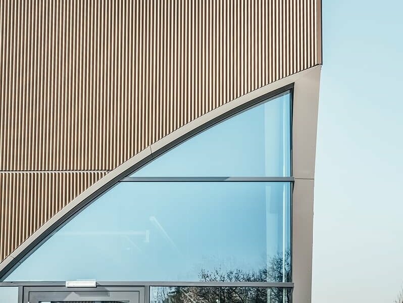 A close-up of the PREFA façade in serrated profile in the colour bronze. A large window can be seen.