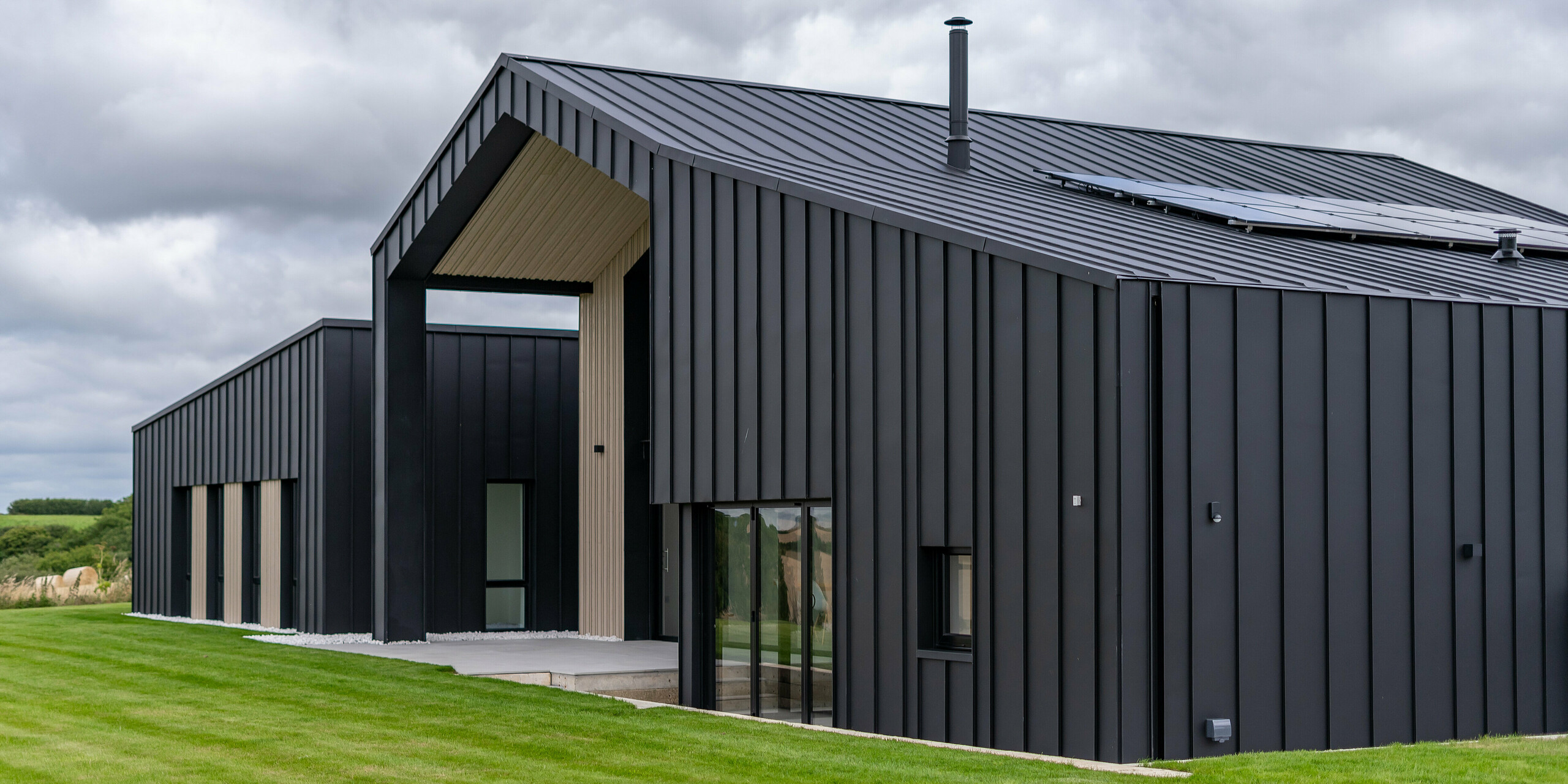 An oblique view of the back of ‘The Hide’ in Cornwall with PREFALZ roof and façade cladding in P.10 anthracite. The clear standing seam look of the aluminium roof and façade creates modern and harmonious lines, which are complemented by wooden elements and the surrounding nature – a perfect interplay of functionality and aesthetics.