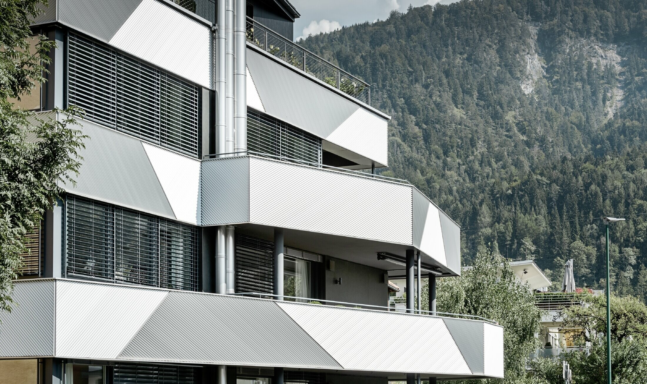Façade design of an apartment building with balconies and loggia with the PREFA zig-zag profile with diagonal installation.