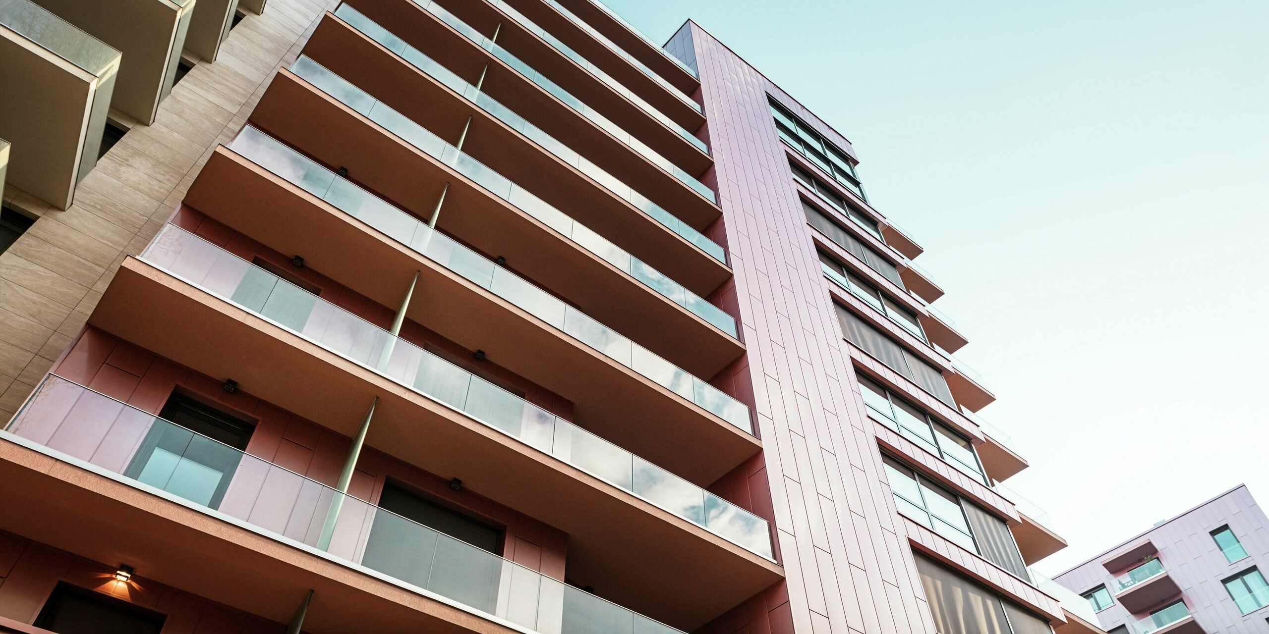 Dynamischer Blick entlang der Aluminiumfassade des Grand Corvin Wohngebäudekomplexes im Budapester Corvin-Viertel. Die vertikale Gliederung der PREFA Sidings in der Sonderfarbe Lachsmetallic prägt das moderne Erscheinungsbild. Die langlebigen, witterungsbeständigen Fassadenpaneele unterstreichen die hochwertige Architektur und setzen einen eleganten Akzent im urbanen Umfeld.