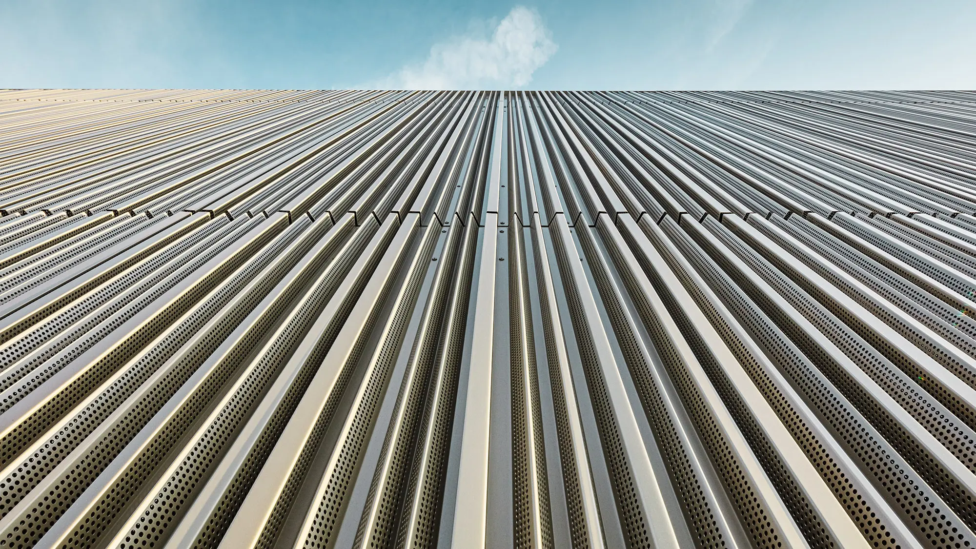The profiled aluminium façade from a worm's eye view, the sky above it.