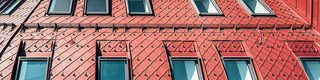 Close-up of the striking roofscape made of oxide red aluminium rhomboid tiles.