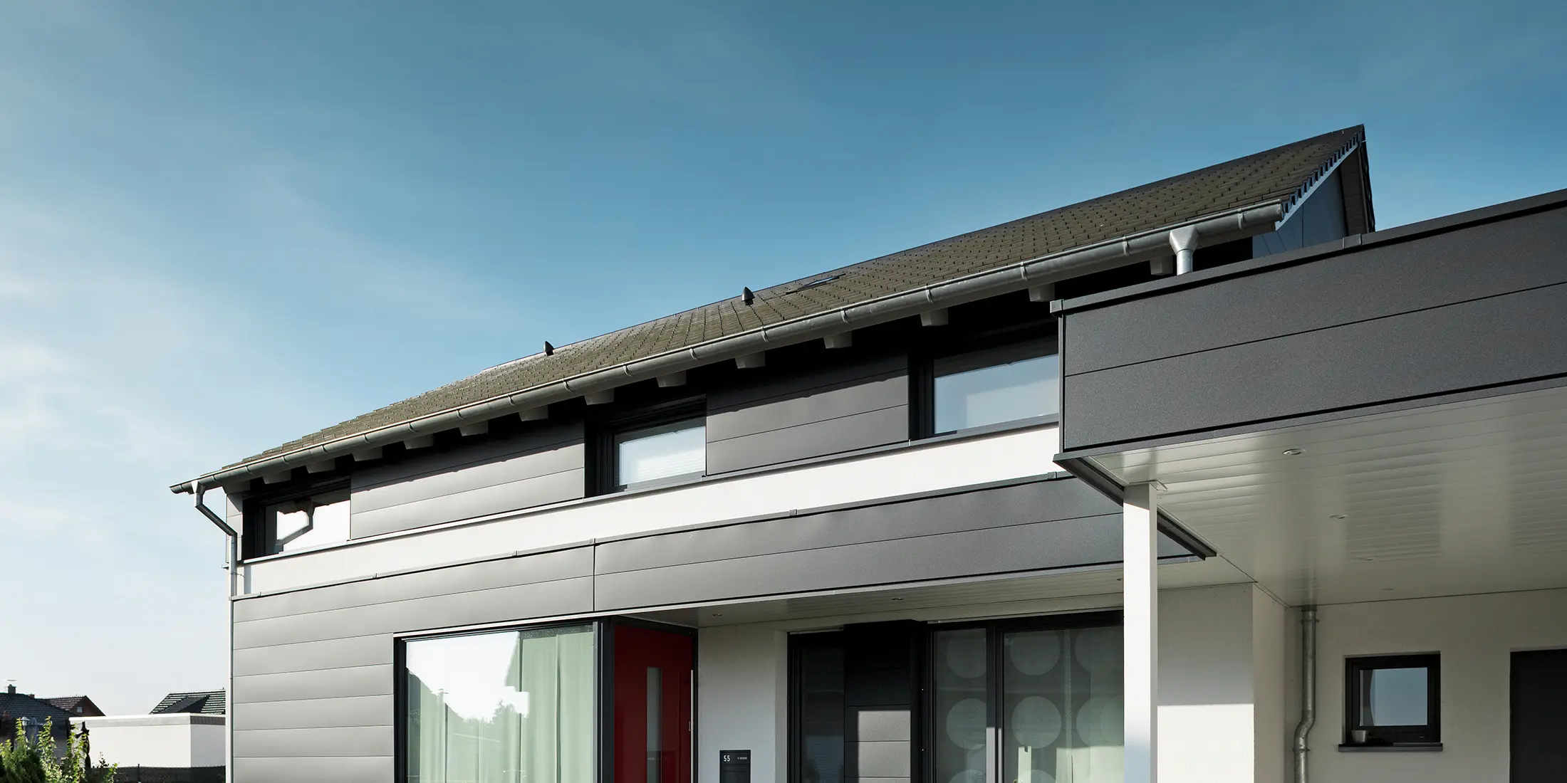 Rückseite eines modernen Einfamilienhauses in Isenbüttel, ausgestattet mit PREFA Aluminium-Sidings in P.10 Anthrazit – ein perfektes Zusammenspiel von Funktionalität und Ästhetik. Die großzügigen Fenster sorgen für ein optisches Highlight und lichtdurchflutete Innenräume.