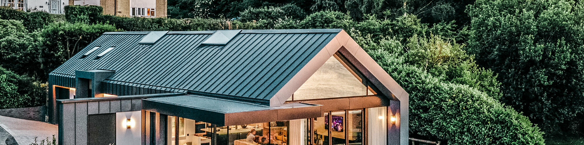 Side view of the bungalow by designed by Mitchell Evans Architects in Cowes on the Isle of Wight. The terrace, the generously glazed front and the evenly laid Prefalz trays are in clear view.