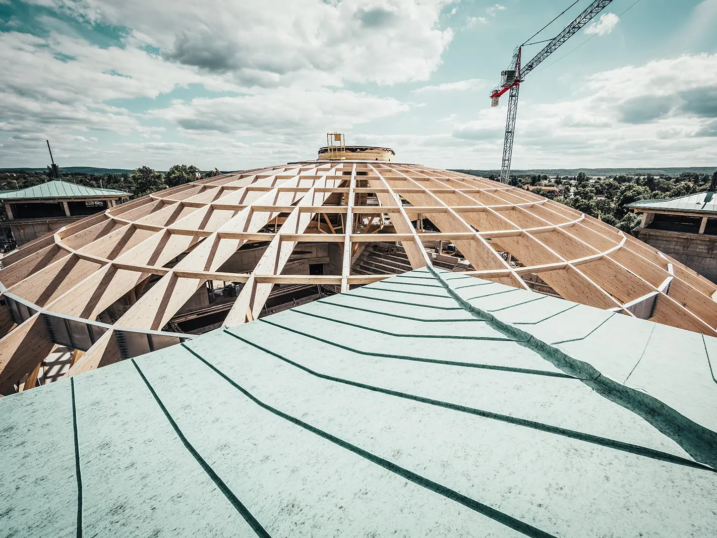 On the picture you can see the biggest laminated cupola in Hungary in the process of completion. In the foreground is the Prefalz roof in patina green. 
