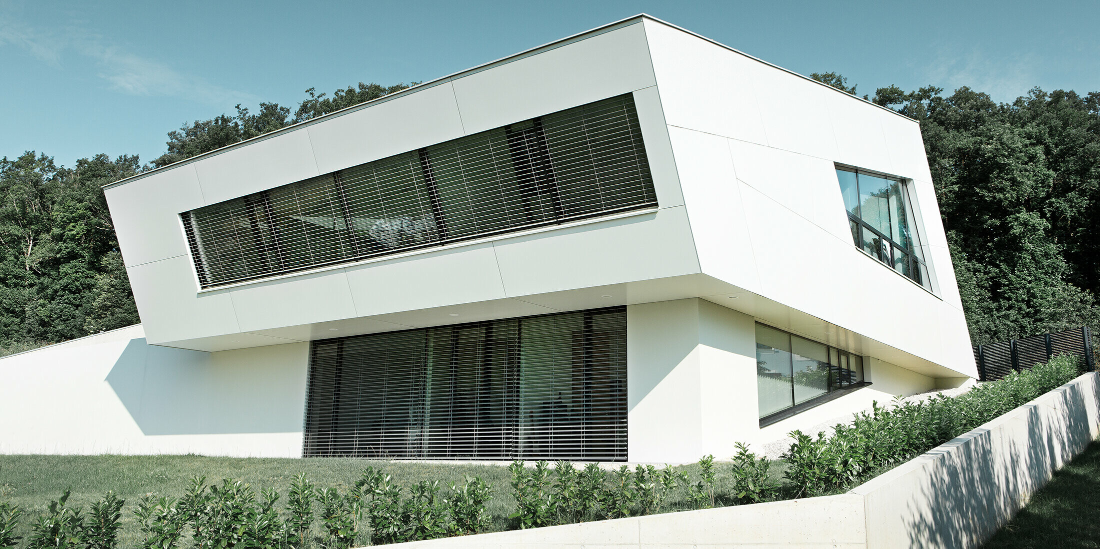 Very modern detached house with a white PREFA composite panel façade and large windows