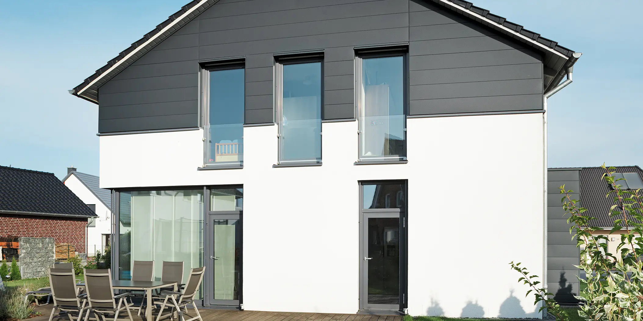Stilvolle Giebelseite eines Einfamilienhauses in Isenbüttel, verkleidet mit langlebigen PREFA Fassadenpaneelen in P.10 Anthrazit für ein zeitgemäßes Design. Die hochwertige Blechfassade und die Hochkantfenster fügen sich harmonisch in die moderne Architektur ein.