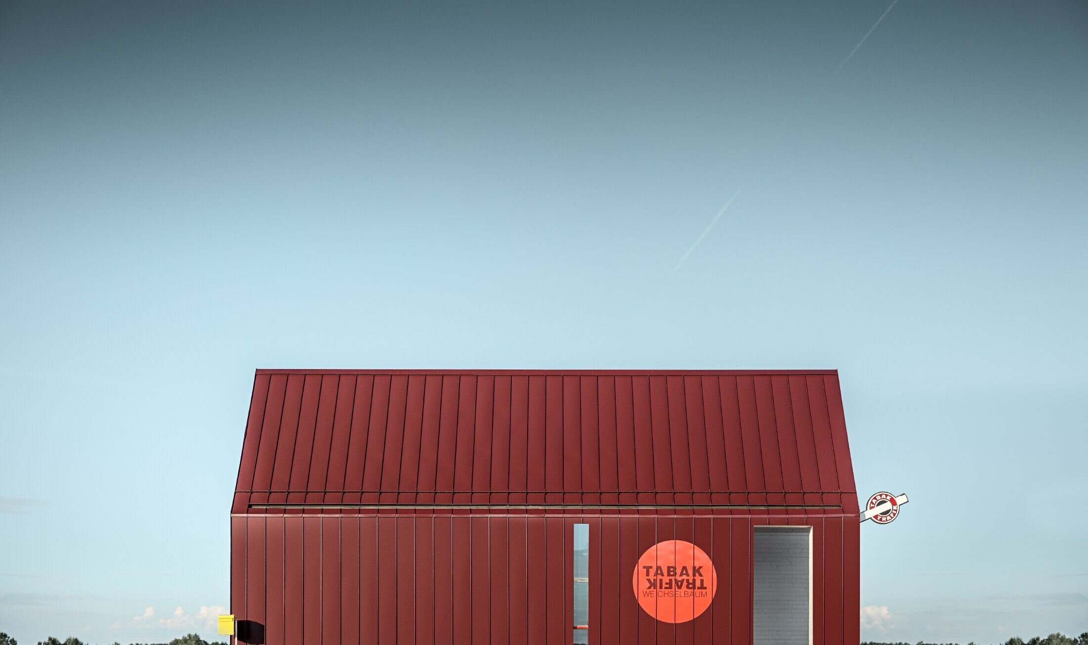 Modern tobacconist with gable roof (without overhanging eaves) and an aluminium coating by PREFA with standing and single lock standing seam in the special colour of black red