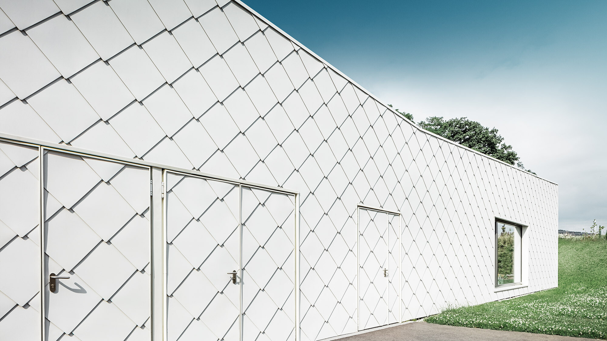 The rhomboid façade tile from the side, with the evenly laid rhomboid façade tiles in view.