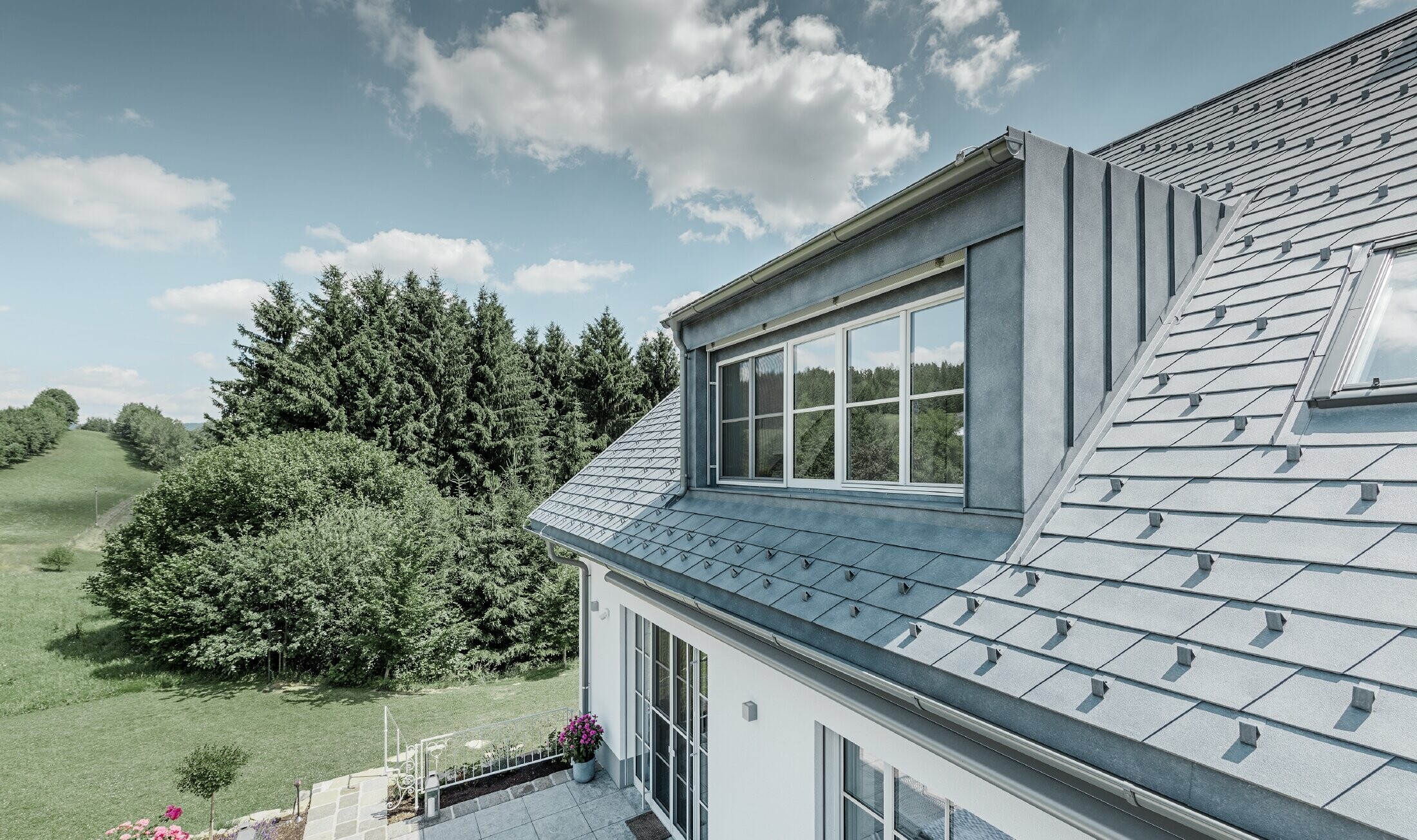 Dormer of the newly refurbished detached house with PREFA roof shingles in stone grey. The dormer is clad in Prefalz (standing steam).