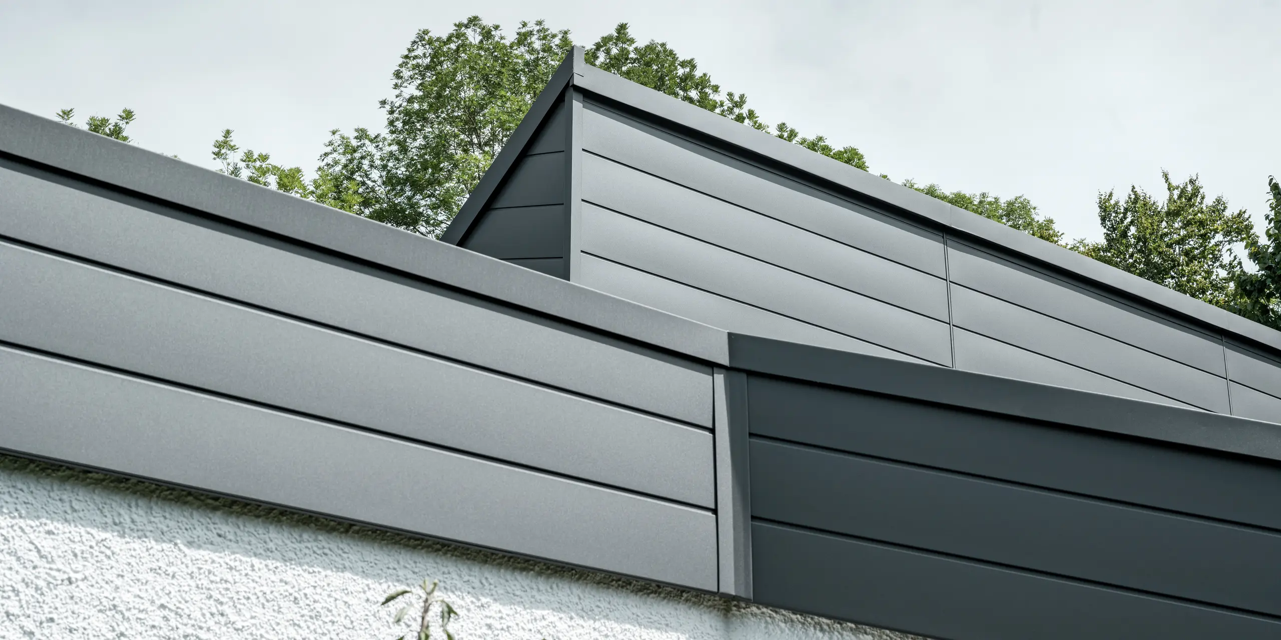 Ein Einfamilienhaus, das mit PREFA Dachschindeln DS.19 in schwarz eingedeckt wurde. Für Teile der Fassade wurden PREFA Sidings in P.10 dunkelgrau verwendet. 