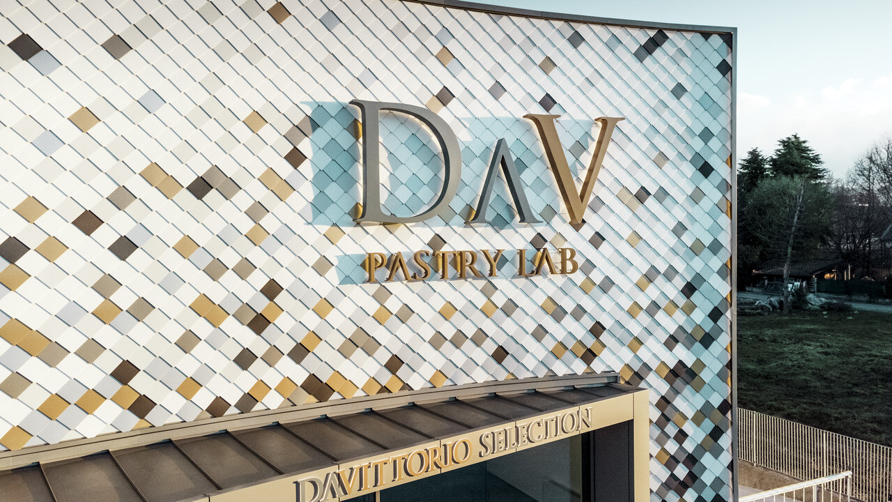 DAV Pastry Lab company building in Bergamo with a speckled rhomboid tile façade in the colours P.10 brown, bronze, P.10 dark grey, maya gold, plain aluminium, P.10 PREFA white and P.10 pure white 