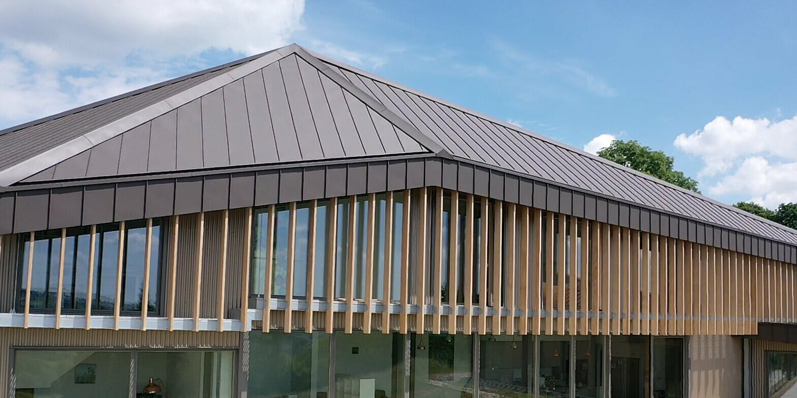 Close-up of a longhouse with PREFA aluminium roof and façade made of individual wooden elements