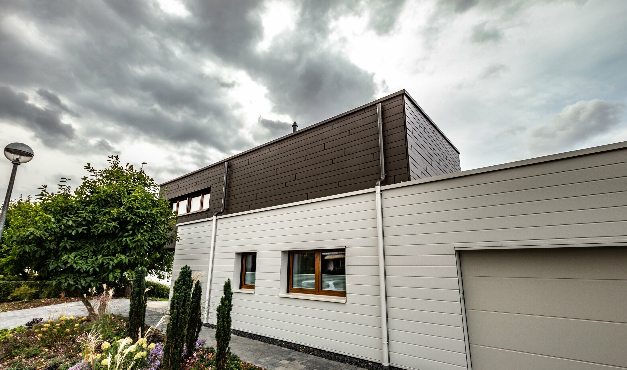 Façade cladding for a garage with horizontal PREFA sidings in white with parapet outlet connector.