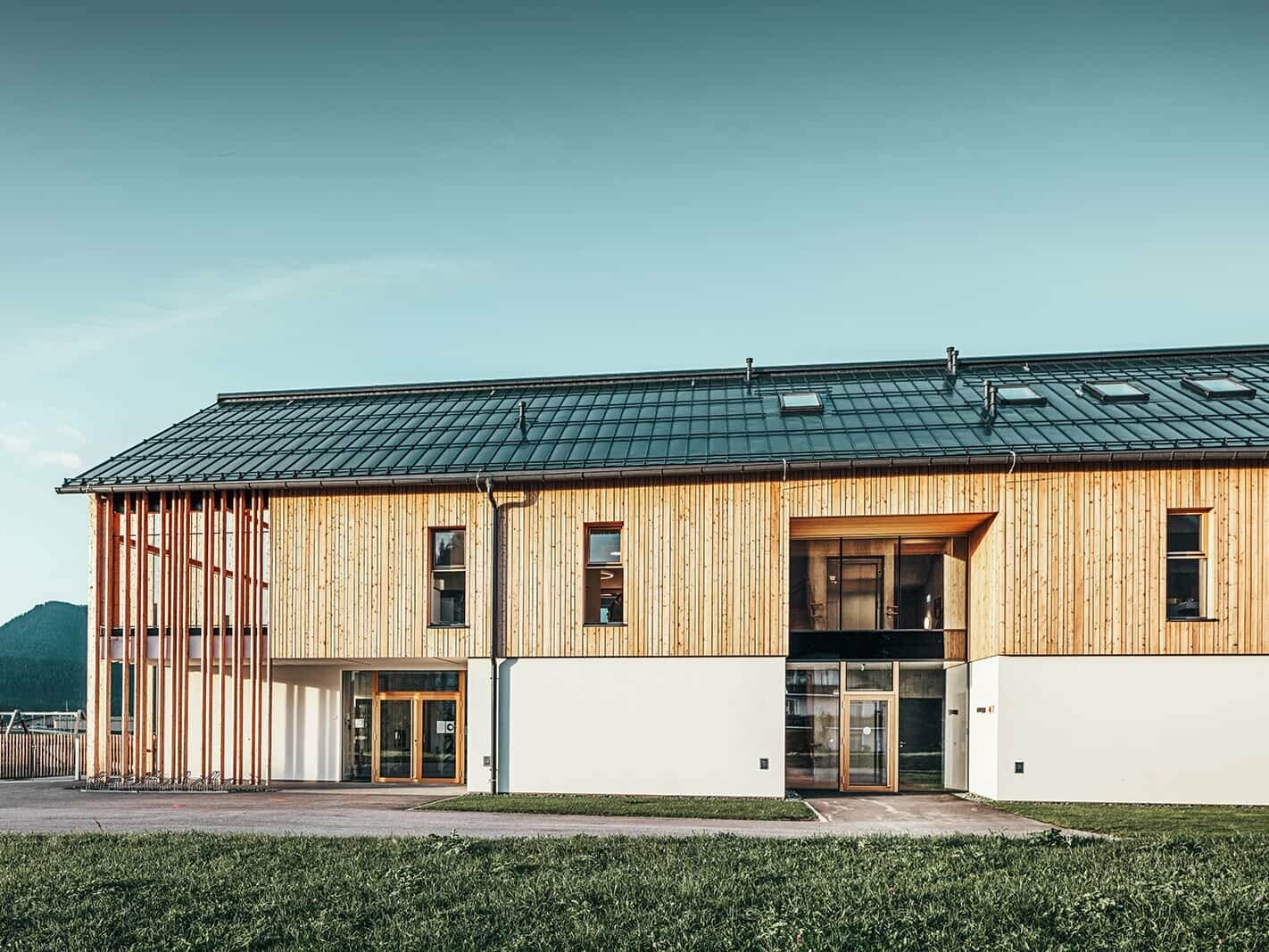 Front view of the kindergarten in Bad Mitterndorf, Austria. The façade is made of wood, the roof is clad with Prefalz in P.10 anthracite