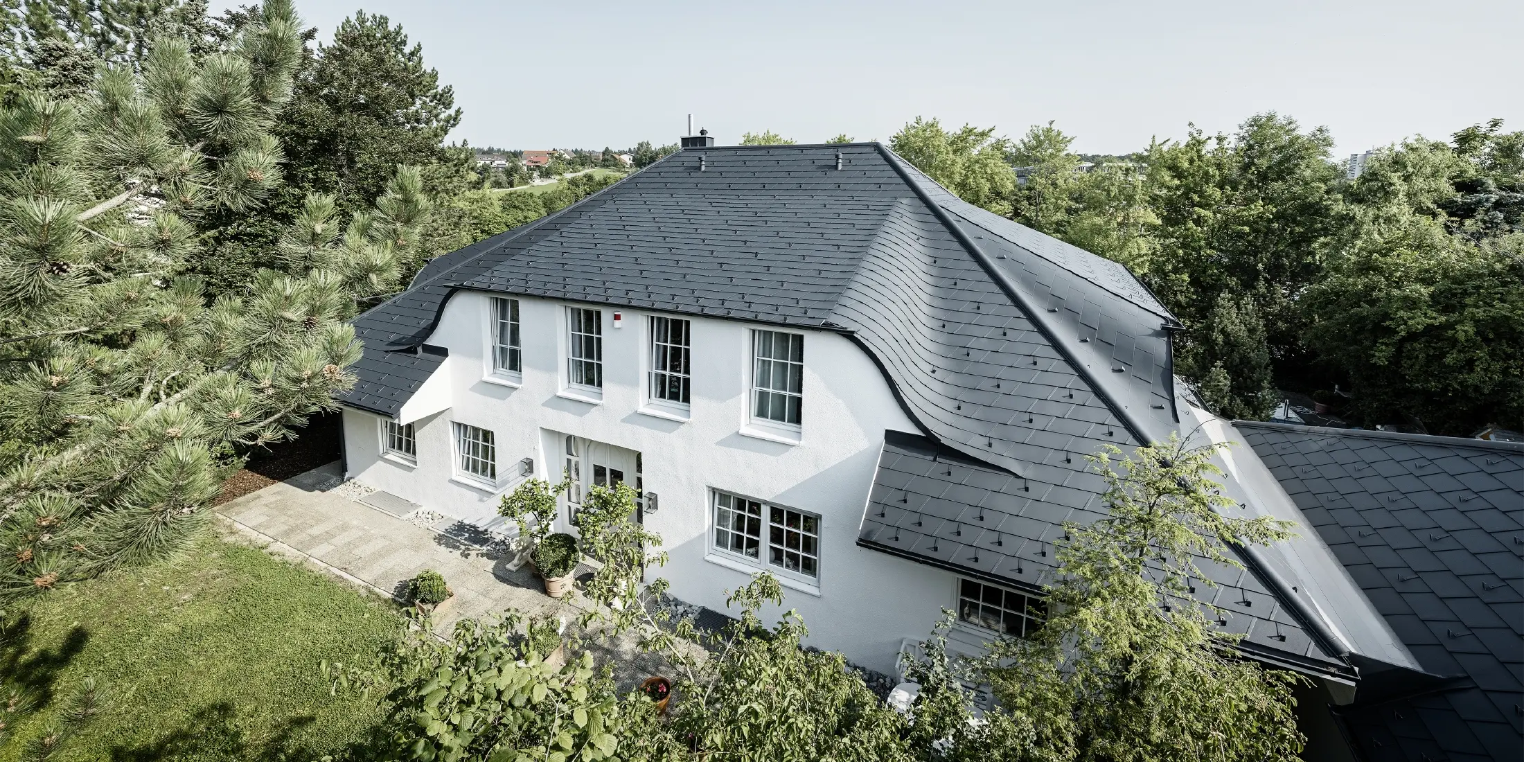 Hipped roof with many curved dormers, covered with DS.19 aluminium roof shingles in anthracite