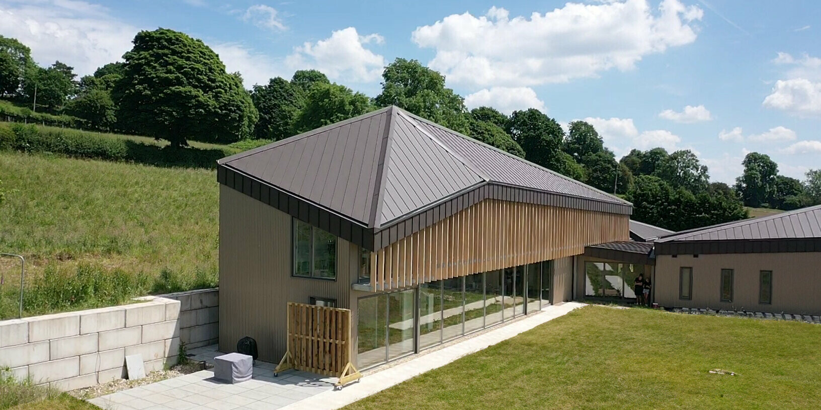 Oblique view of a longhouse with a standing seam roof made of aluminium in brown