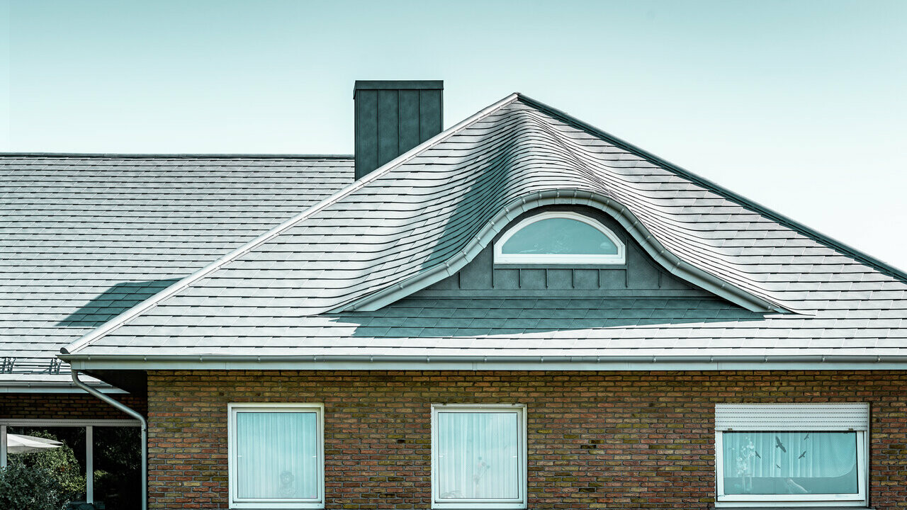 Single-family house with dormer roof covered with PREFA roof shingles in P.10 stone grey 