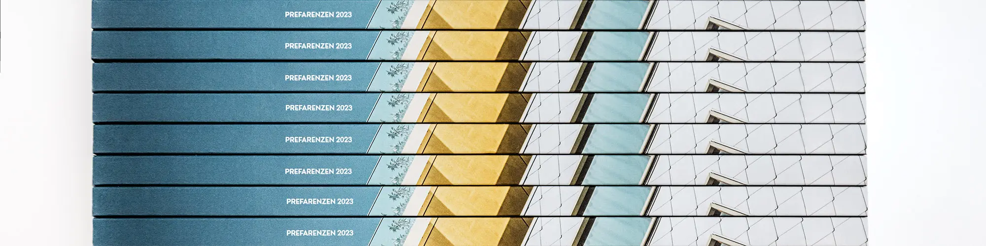 Close-up of several book spines of the PREFARENZEN book 2023 stacked on top of each other.