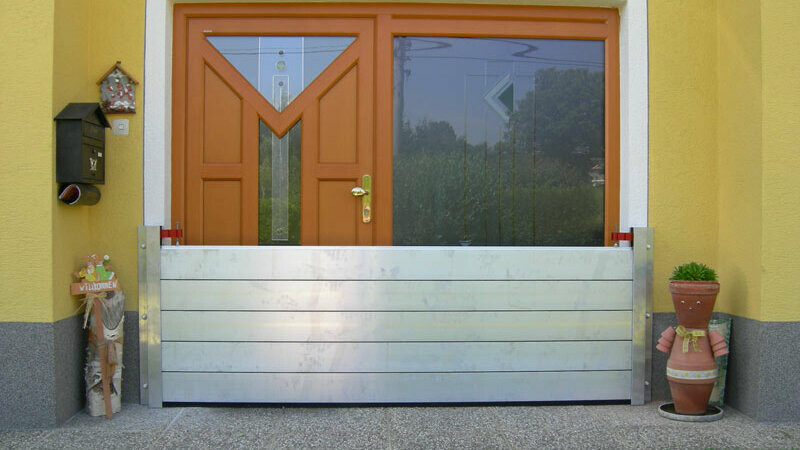 Front door of a family home with the modern PREFA flood protection system 