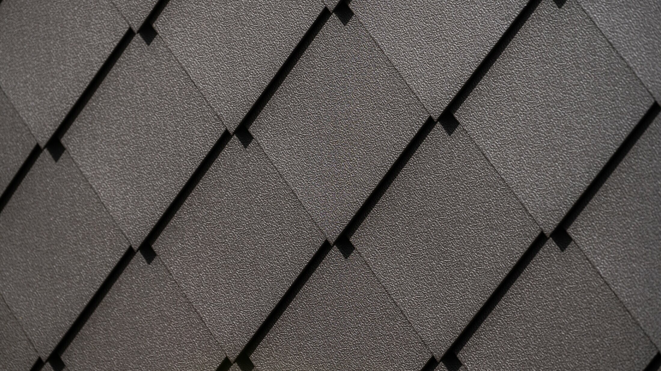 Close-up of PREFA rhomboid façade tile 29 × 29 in nut brown with stucco finish