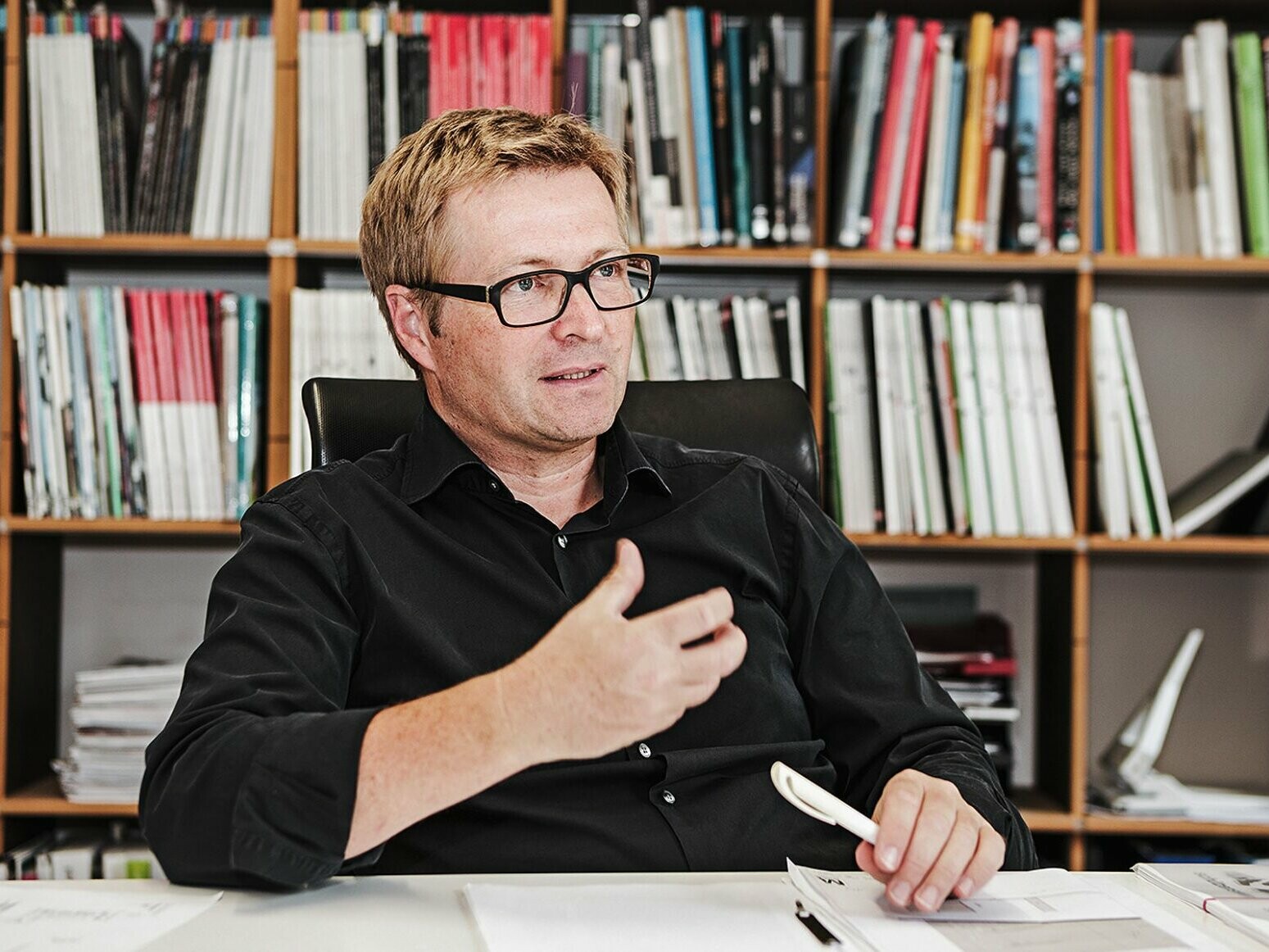 Portrait of architect Christian Mang with a bookcase in the background
