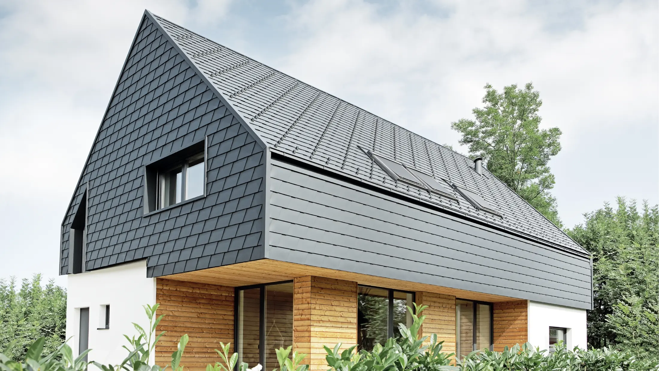 Detached house with gable roof, roofed with PREFA roof shingles in P.10 anthracite, the shingles were also installed on the façade on the upper floor and on the gable.