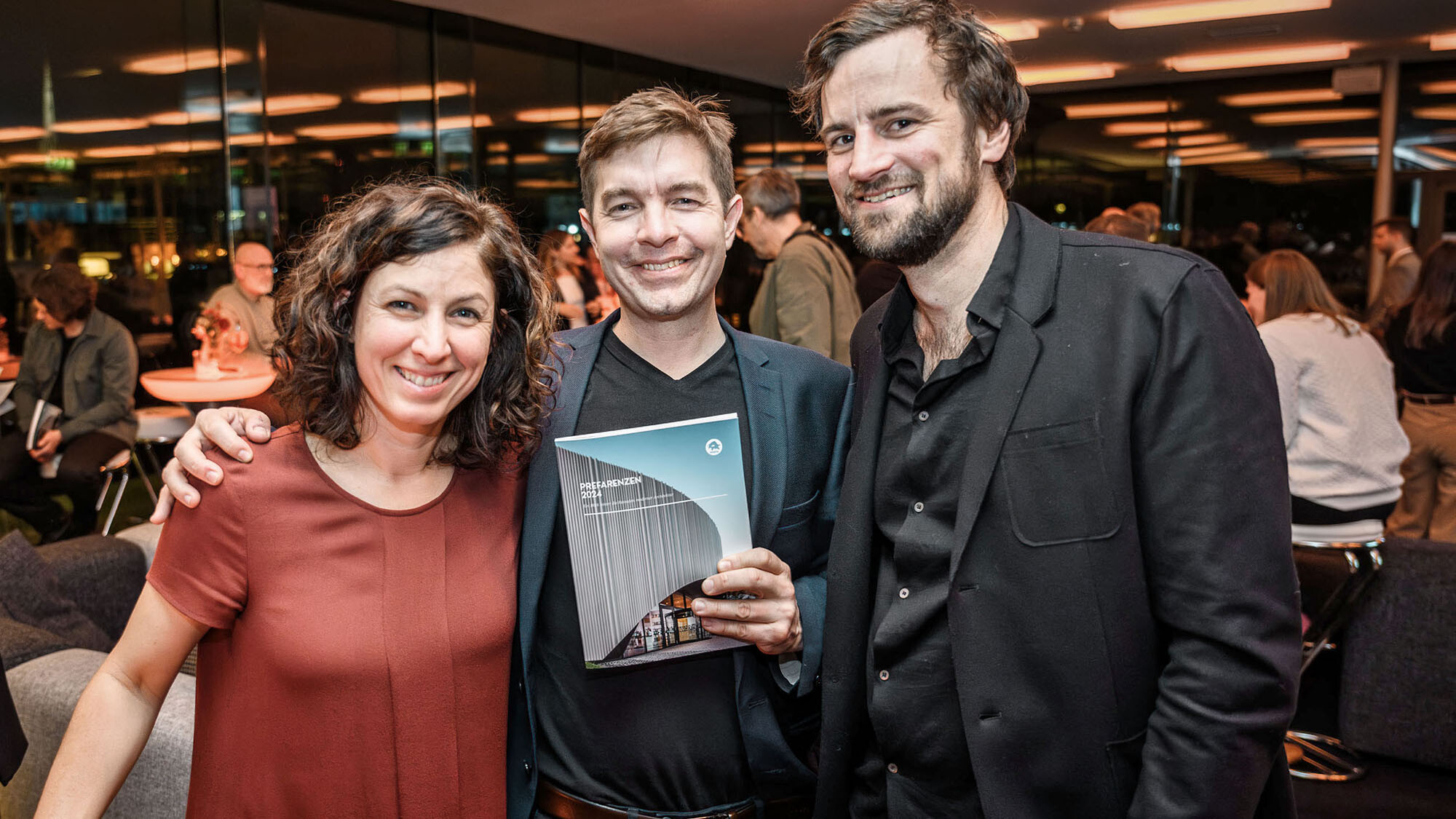 Architect Susi Matt, architect Mario Dallaserra, holding the PREFARENZEN book 2024 in his hand, and architect Benedikt Hörmann.